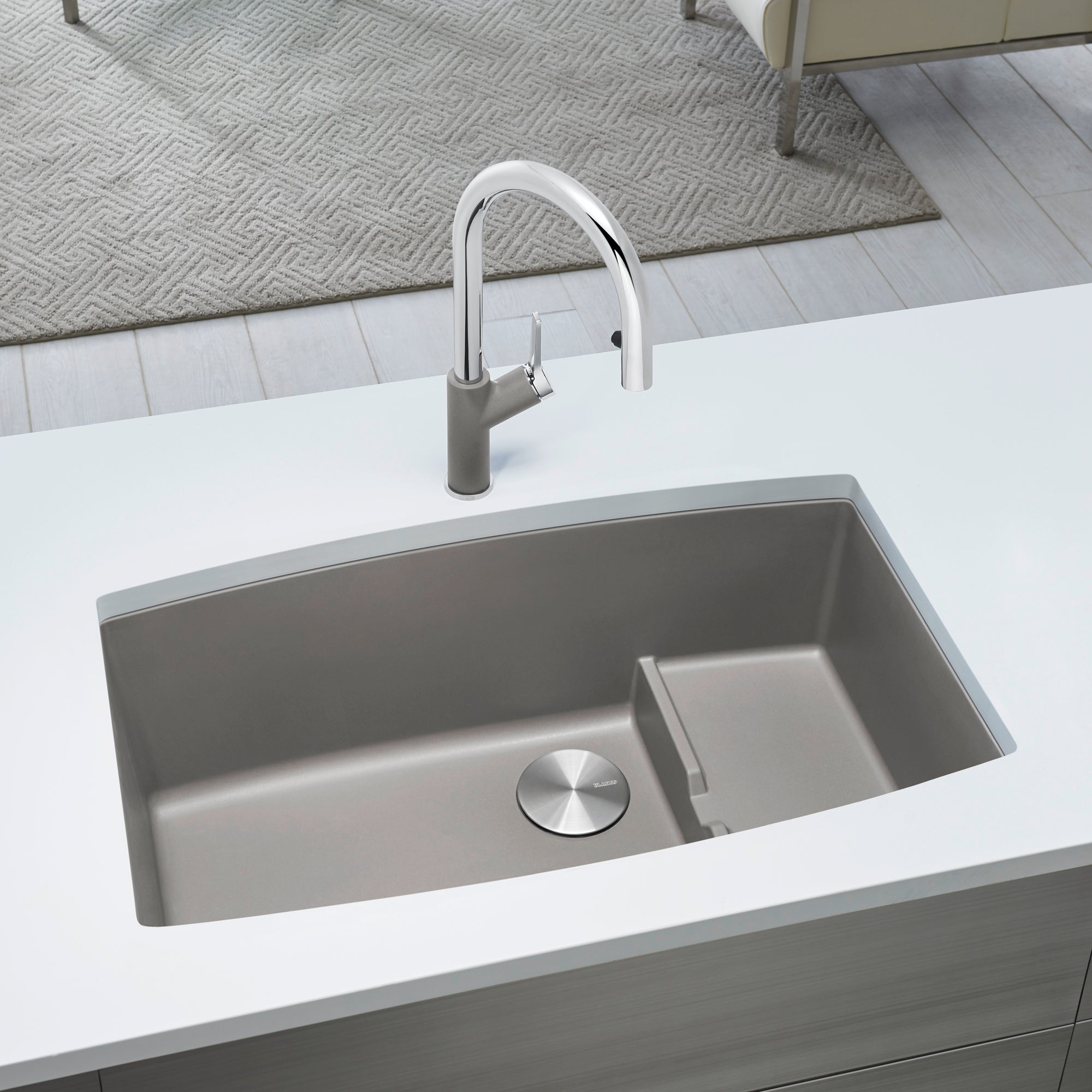 Truffle undermount kitchen sink with two compartments and chrome pull-down faucet installed in white countertop.