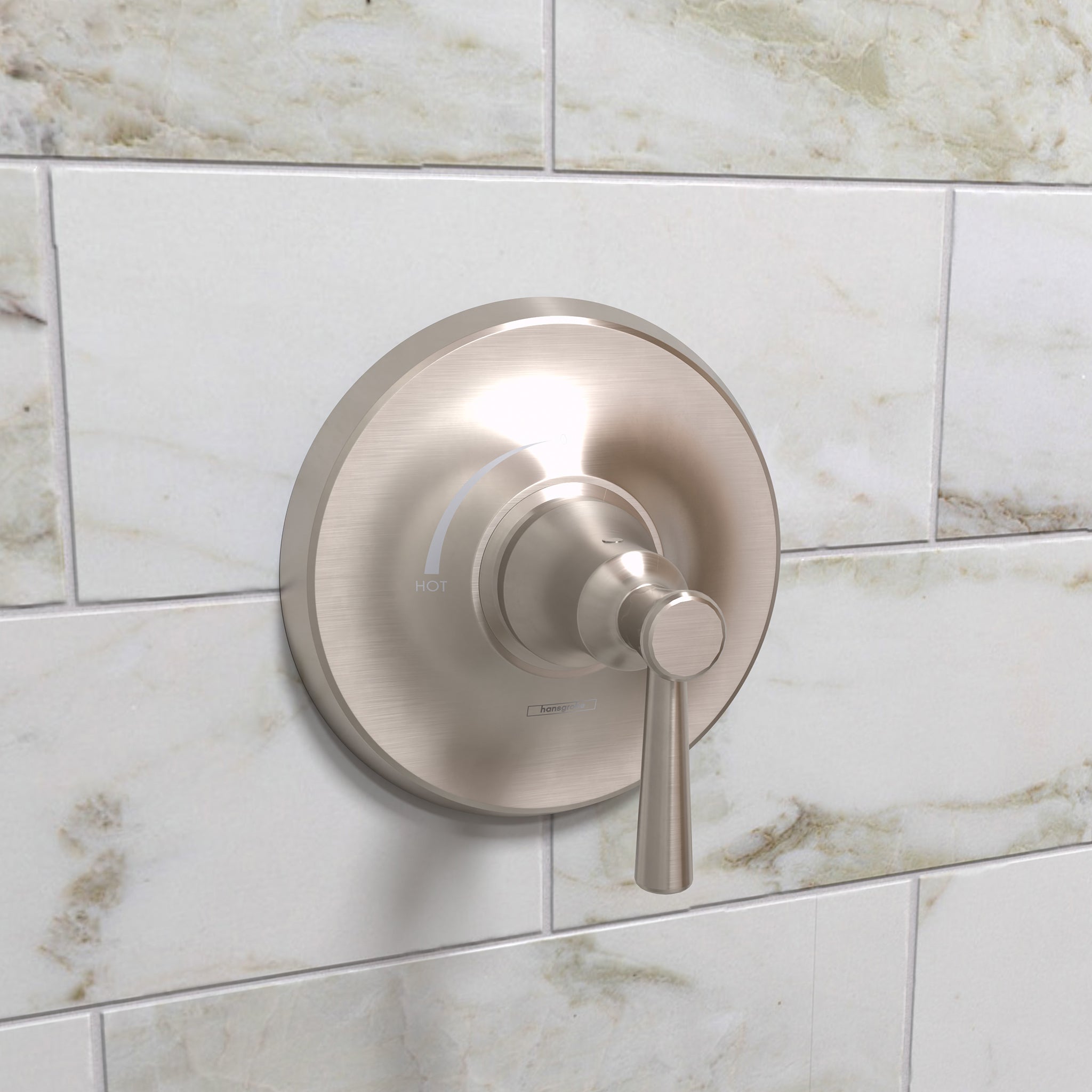 Brushed nickel shower valve trim with circular backplate and lever handle mounted on marble subway tile wall.