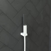 Matte white rectangular handshower with perforated showerhead mounted on wall with white supply hose.