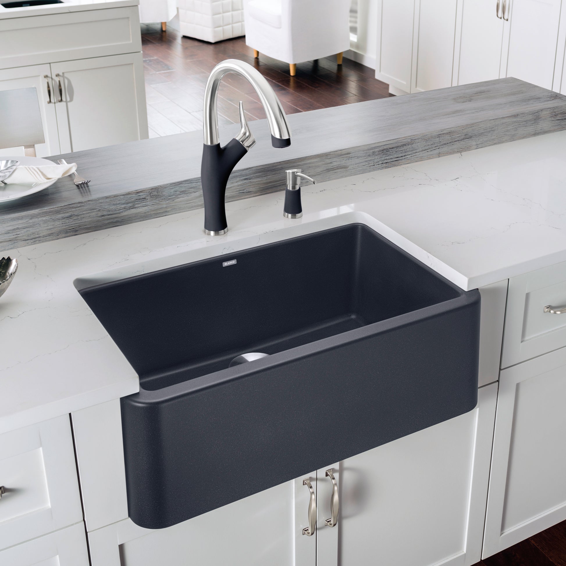 Anthracite apron front kitchen sink with chrome pull-down faucet and matching soap dispenser installed in white cabinetry.