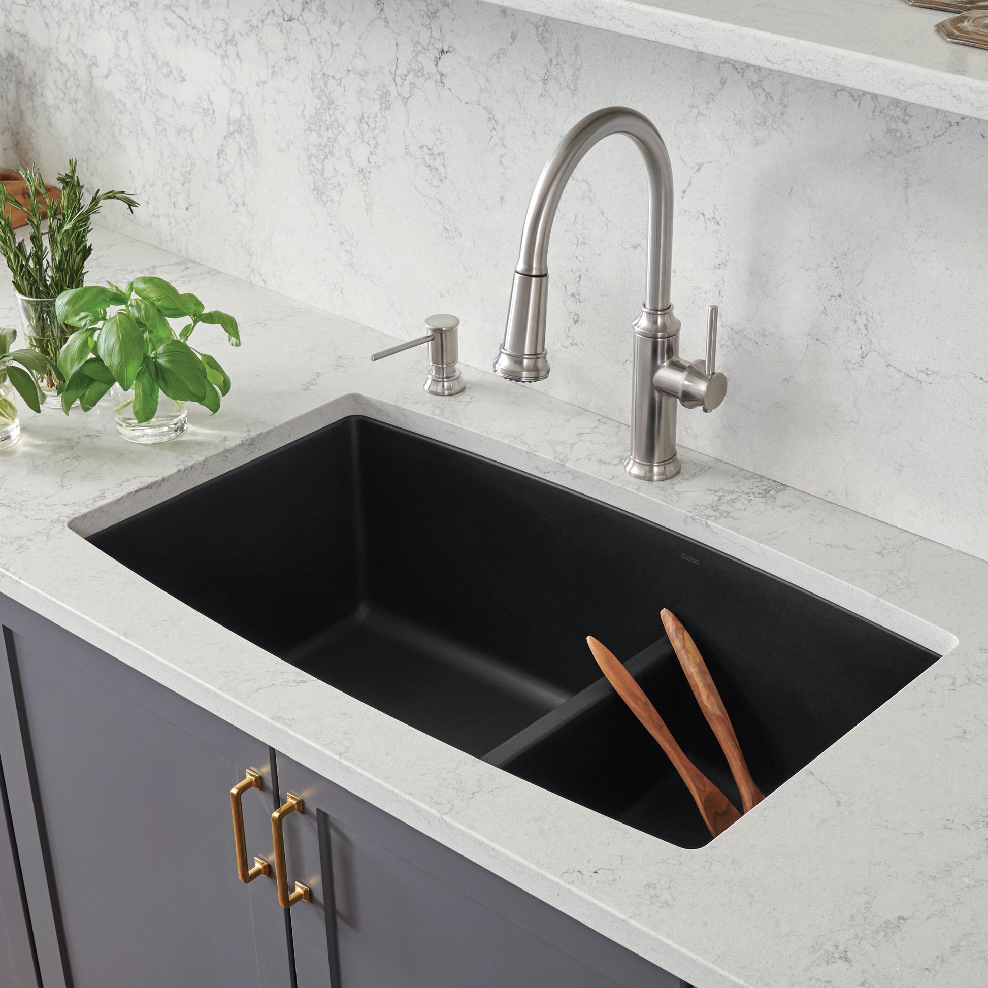 Coal black undermount double bowl kitchen sink with low divide and stainless steel faucet in marble countertop.