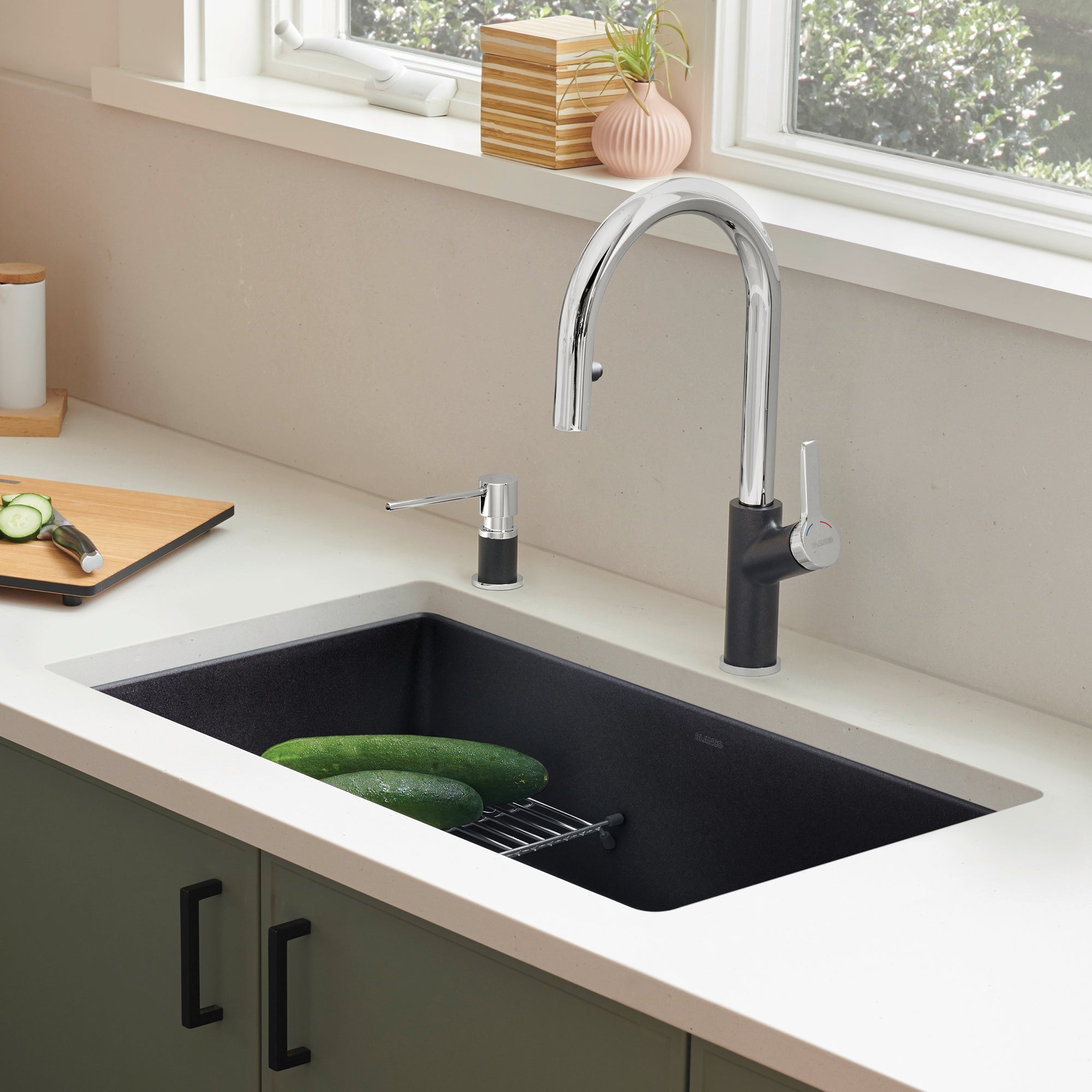 Coal black single bowl undermount kitchen sink with chrome pull-down faucet and matching soap dispenser installed in white co