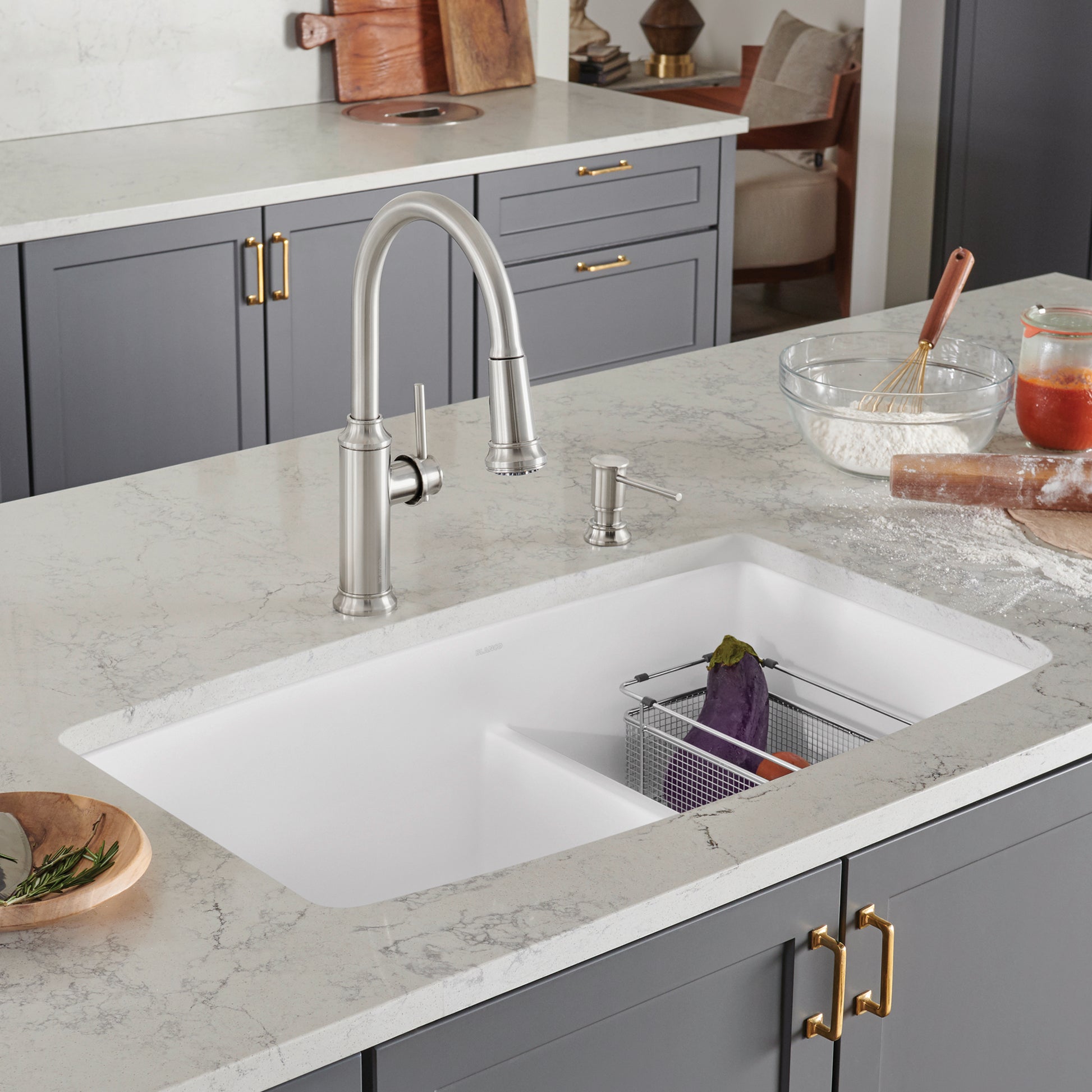 White undermount double bowl kitchen sink with low divide and stainless steel faucet installed in marble countertop.