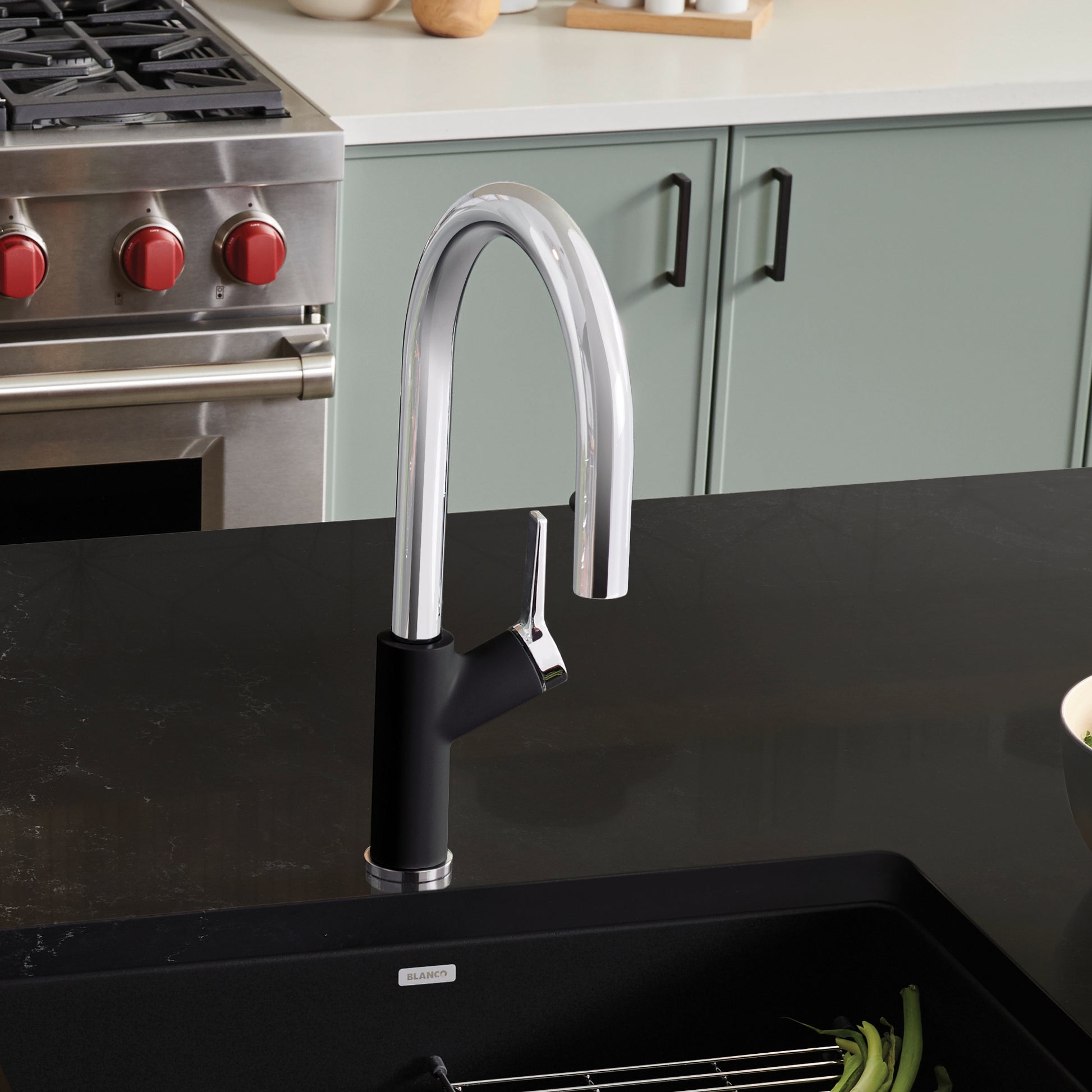 Chrome and black pull-down kitchen faucet with curved spout installed over black sink in modern kitchen.