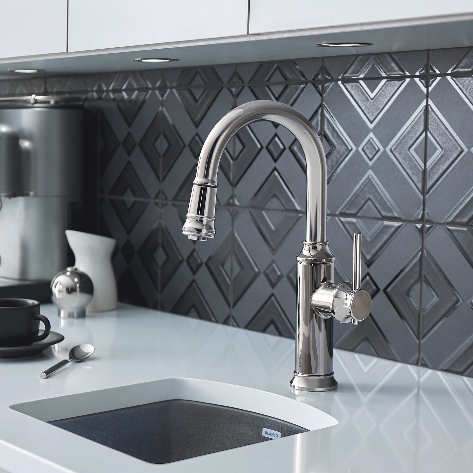 Chrome pull-down kitchen faucet with curved spout and single lever handle mounted above white sink.