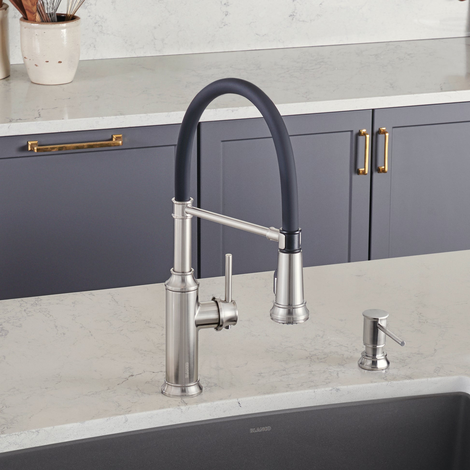 Stainless steel kitchen faucet with black pull-down spray hose and matching soap dispenser on marble countertop.