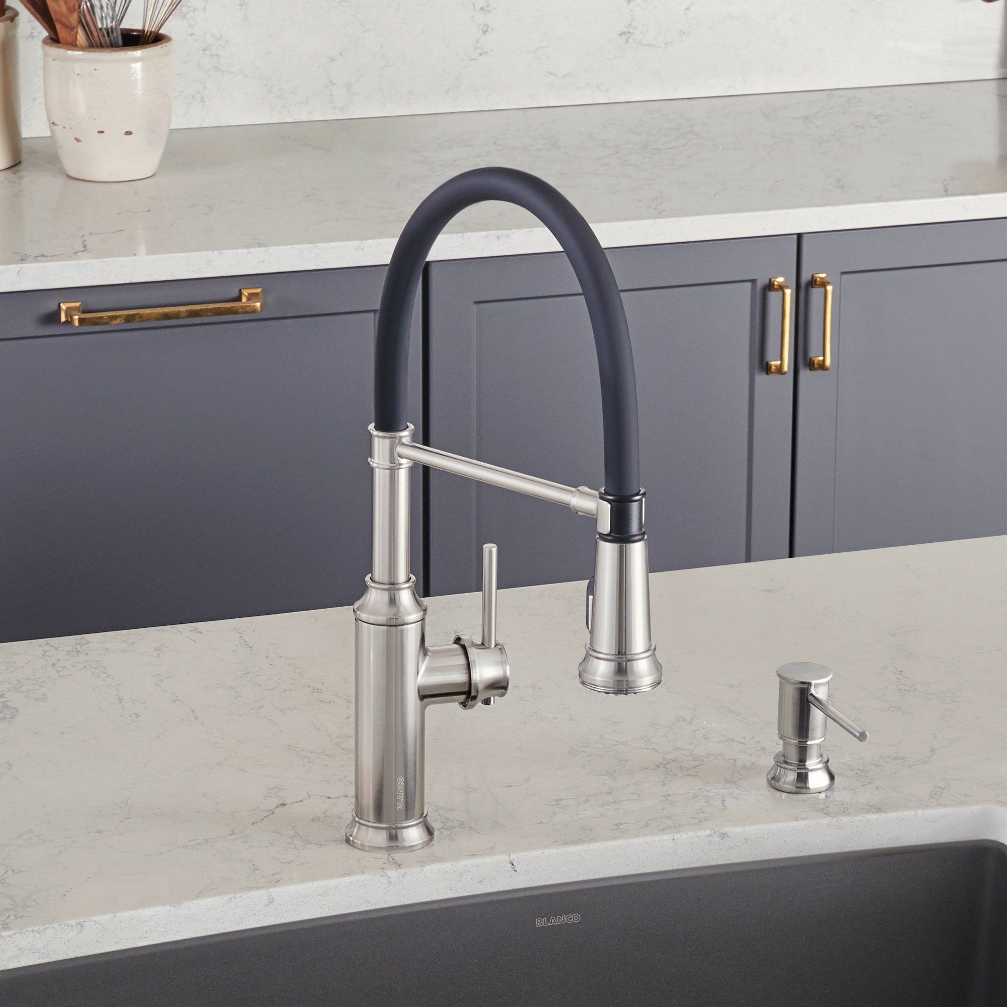 Stainless steel kitchen faucet with black pull-down spray hose and matching soap dispenser on marble countertop.