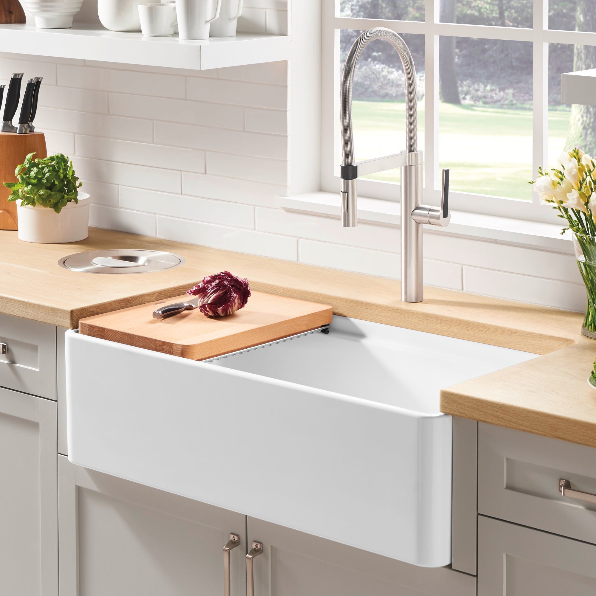 White ceramic apron-front kitchen sink with single bowl and stainless steel faucet.