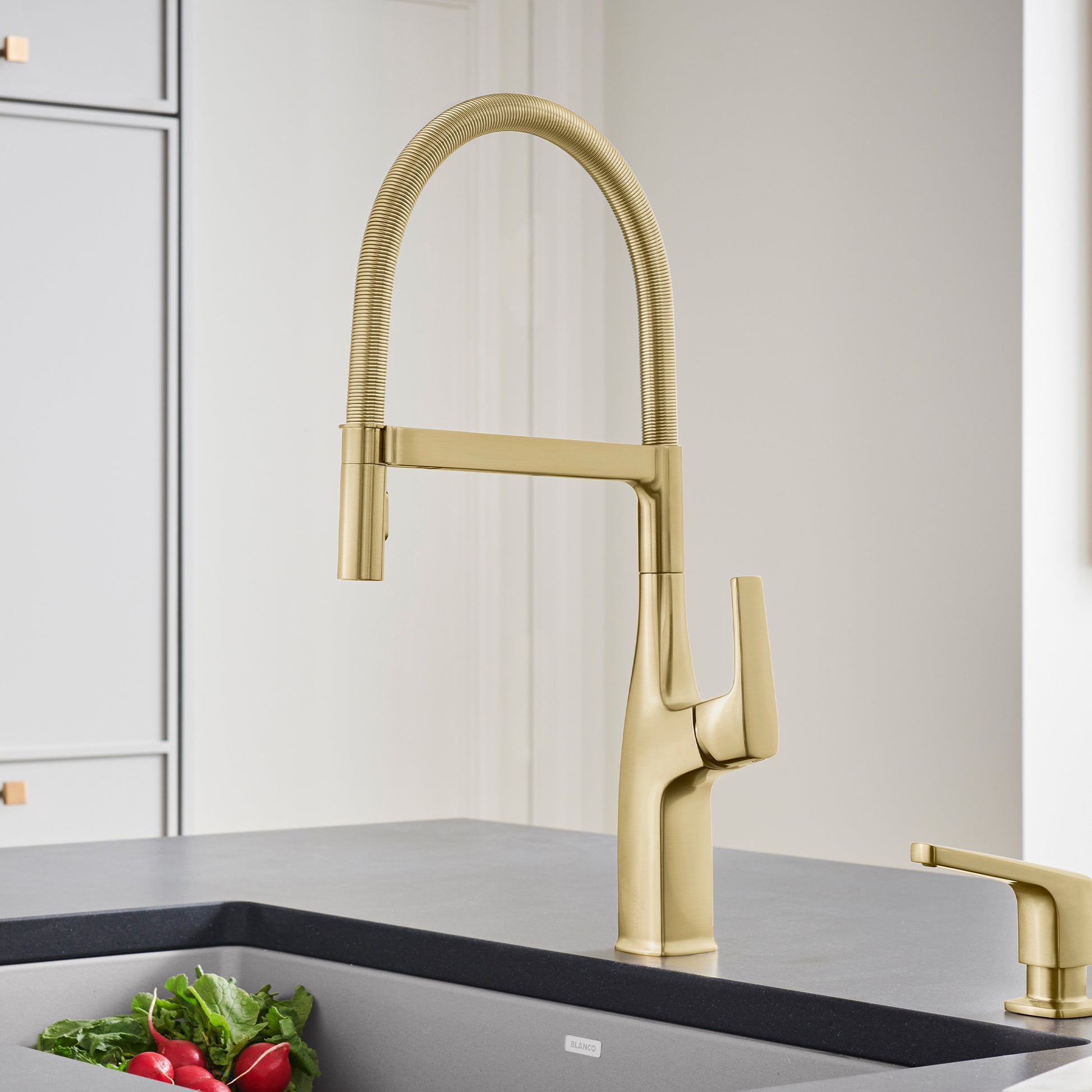 Satin gold semi-pro kitchen faucet with high arched spout, flexible hose, and single lever handle mounted above sink.