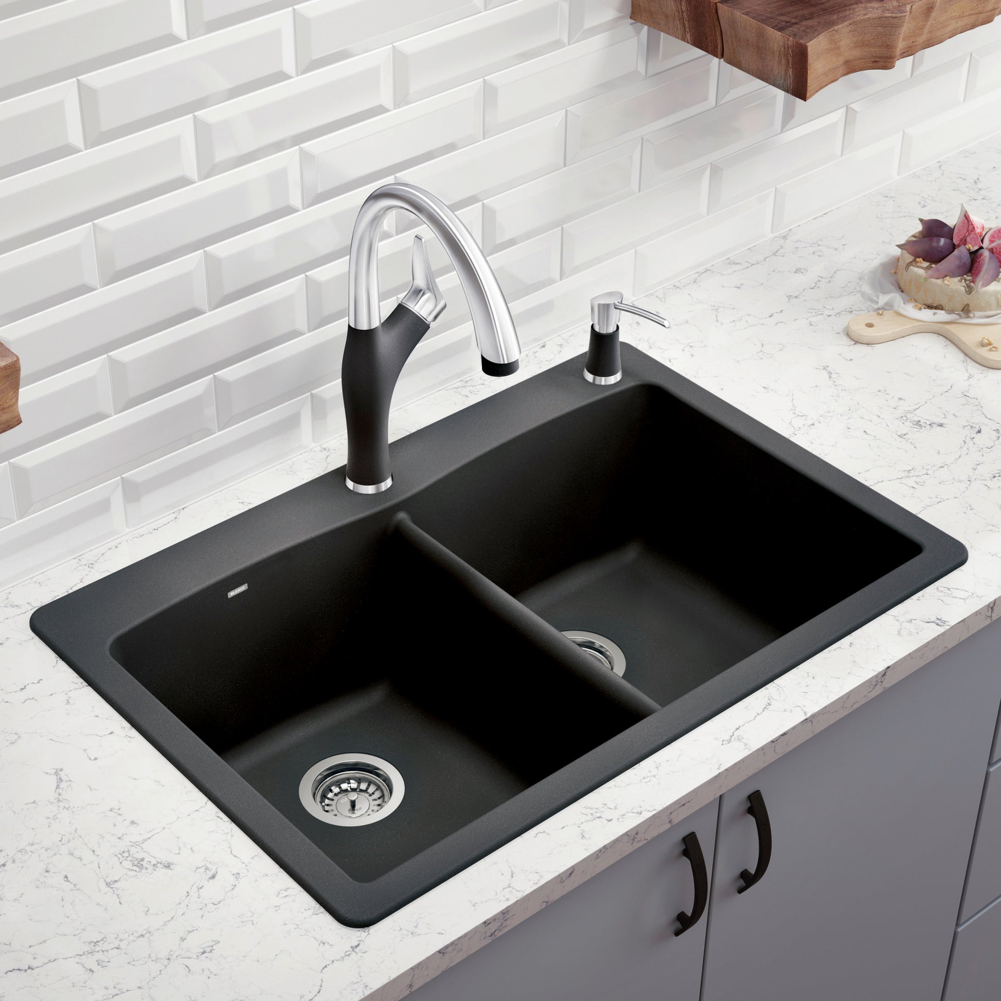 Anthracite double bowl drop-in kitchen sink with chrome faucet and soap dispenser installed in white countertop.