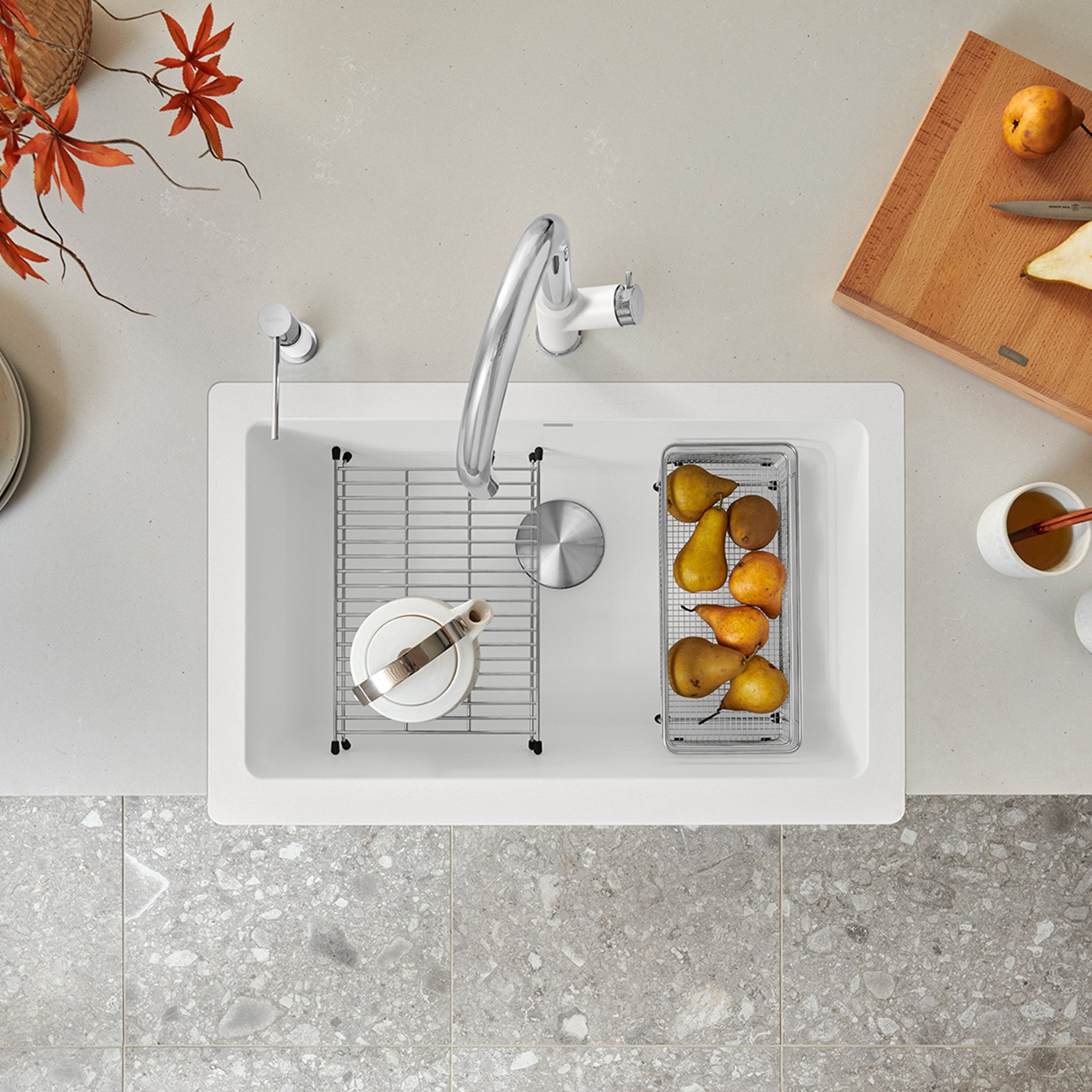 White apron front farmhouse sink with single basin, stainless steel faucet, and included grid and strainer baskets.