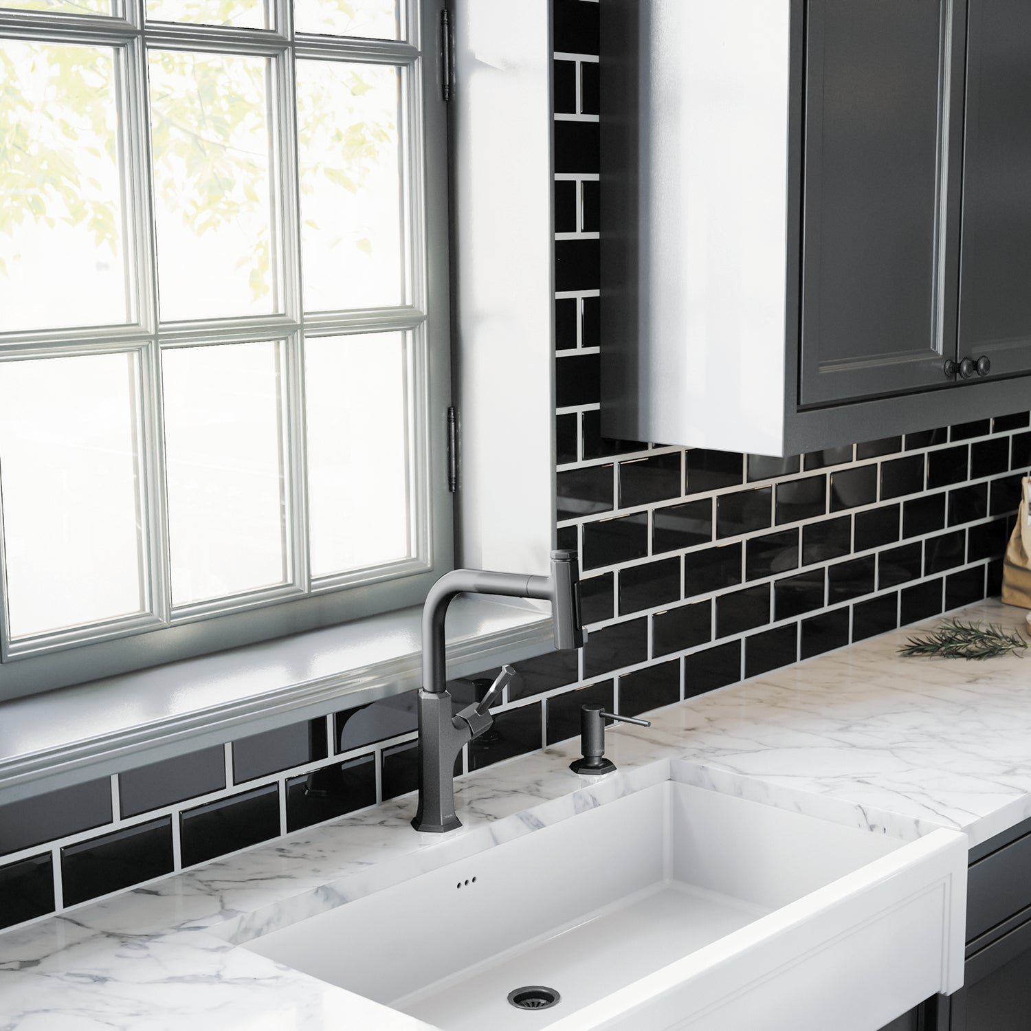 Matte black wall-mounted soap dispenser with cylindrical pump mounted above a white farmhouse sink.