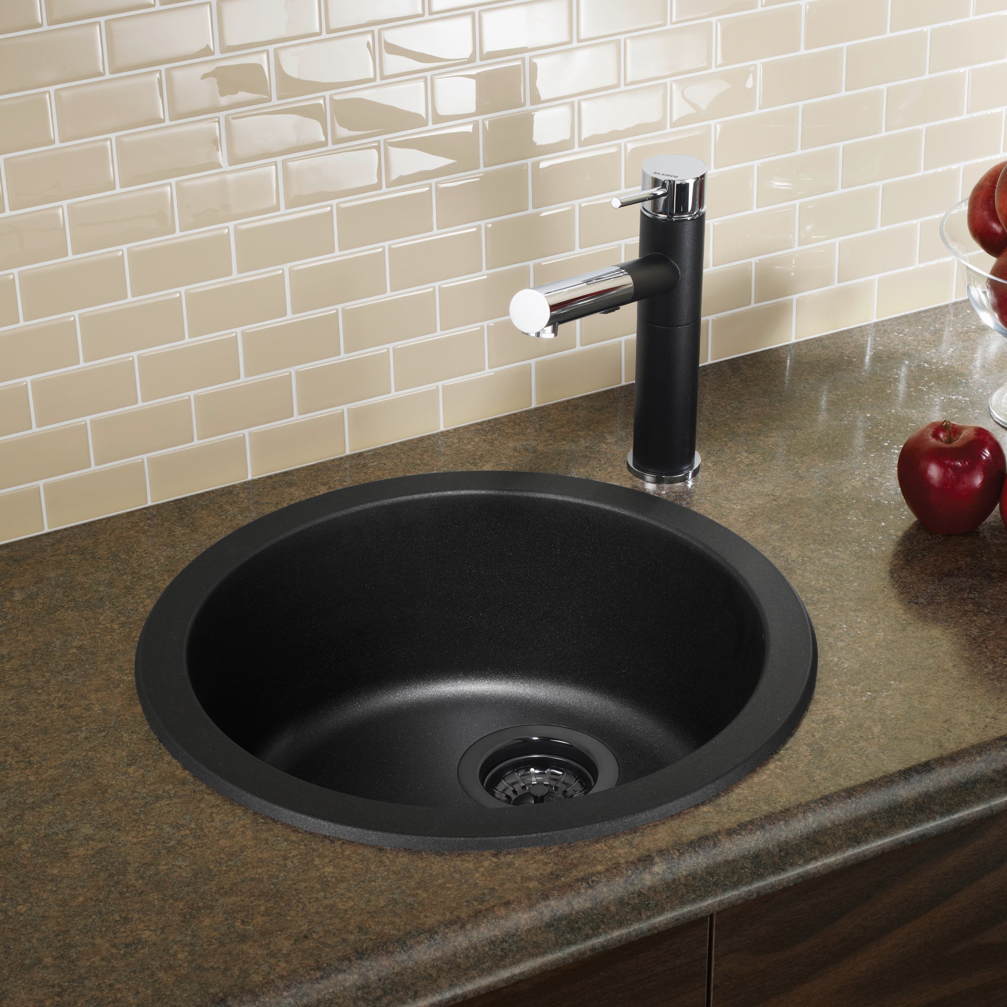 Round anthracite sink mounted in countertop with black pull-down faucet and drain strainer visible.