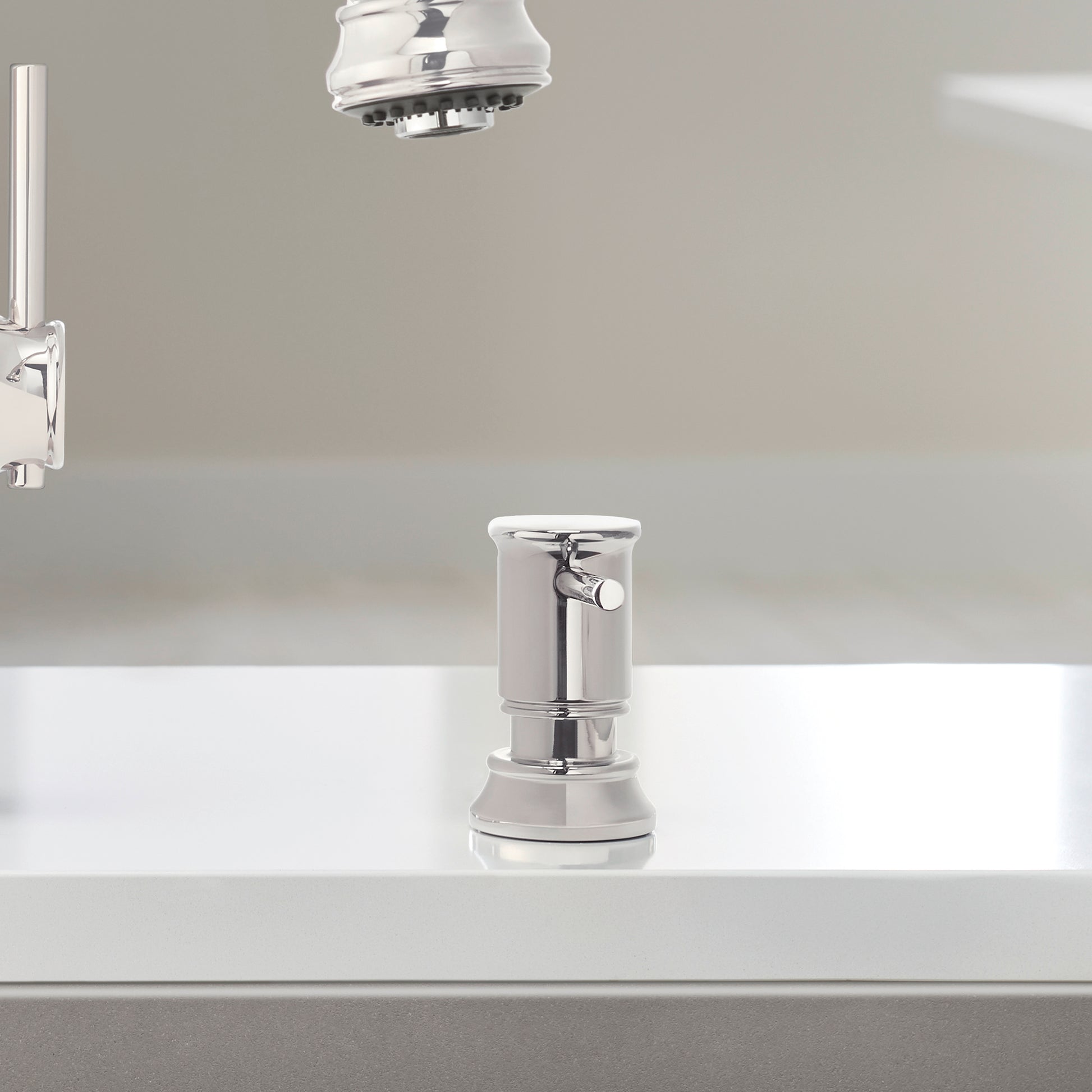 Chrome soap dispenser with cylindrical pump body and rounded top, mounted on countertop.