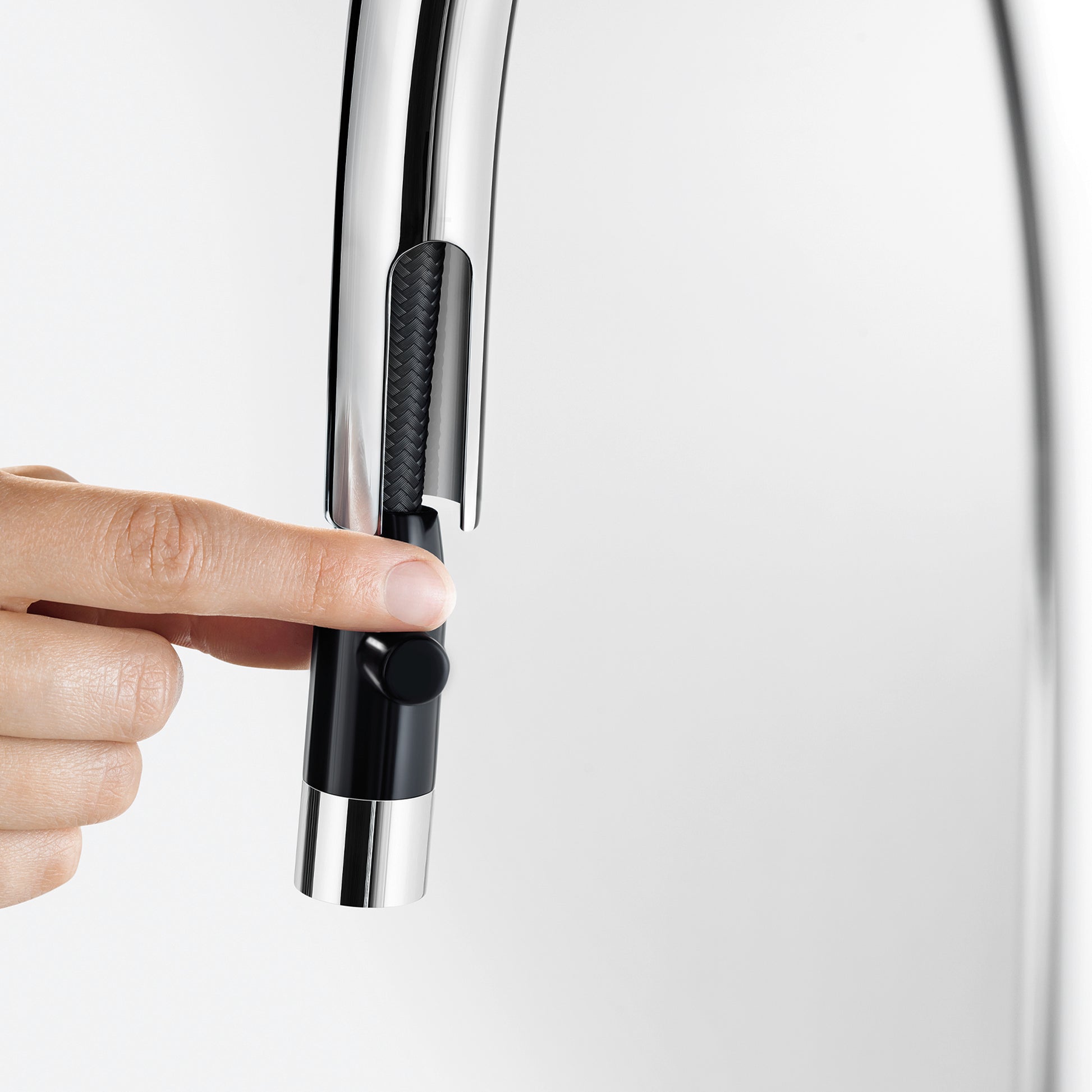 Chrome and black pull-down kitchen faucet spout held in hand, showing textured grip section and trigger control.