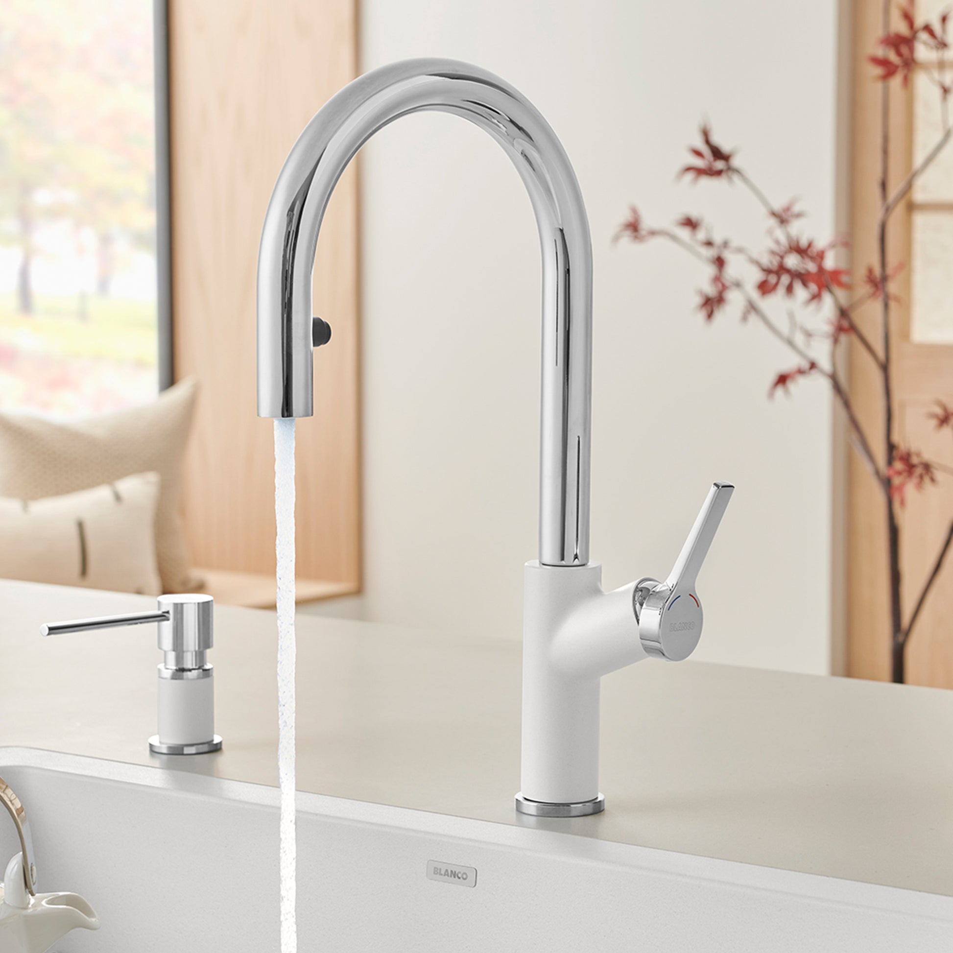 Chrome and white pull-down kitchen faucet with curved spout and single lever handle installed on white countertop.