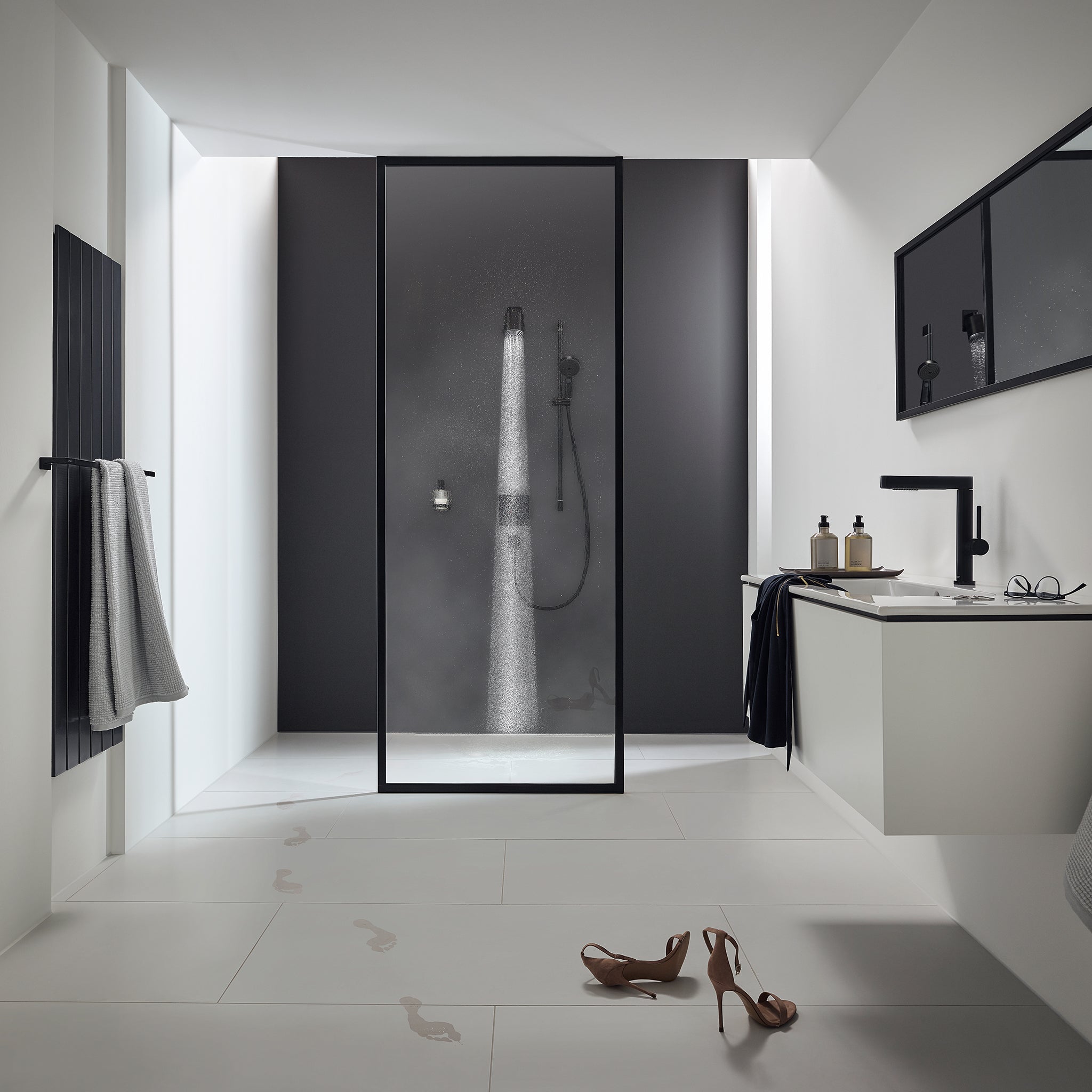 Matte black shower head mounted on wall above shower enclosure with water spray visible.