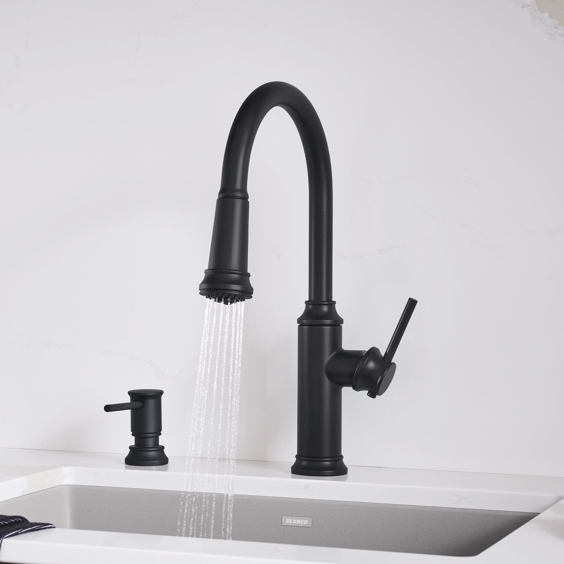 Matte black pull-down kitchen faucet with curved spout, side lever handle, and matching soap dispenser on white sink.