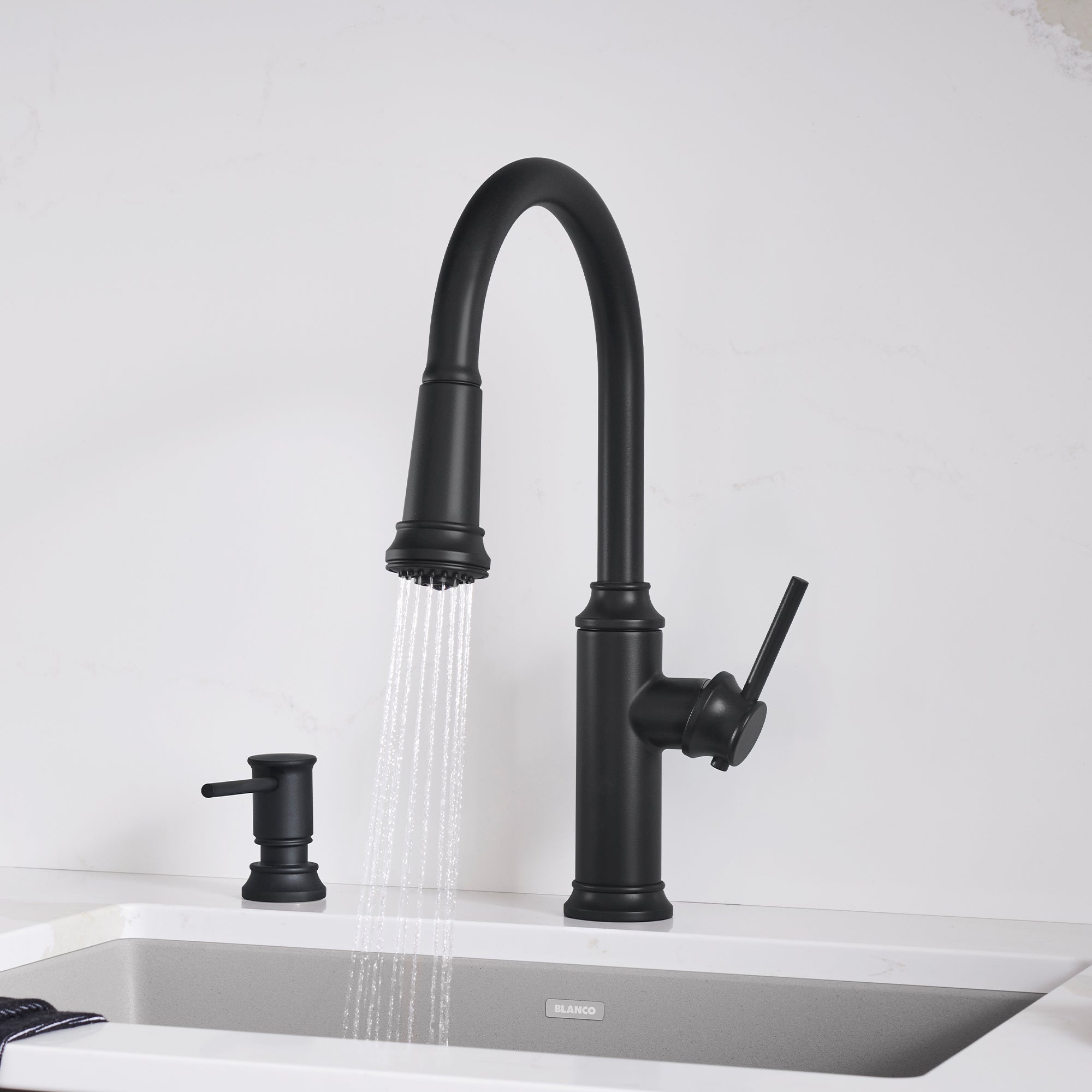 Matte black pull-down kitchen faucet with curved spout, side lever handle, and matching soap dispenser on white sink.
