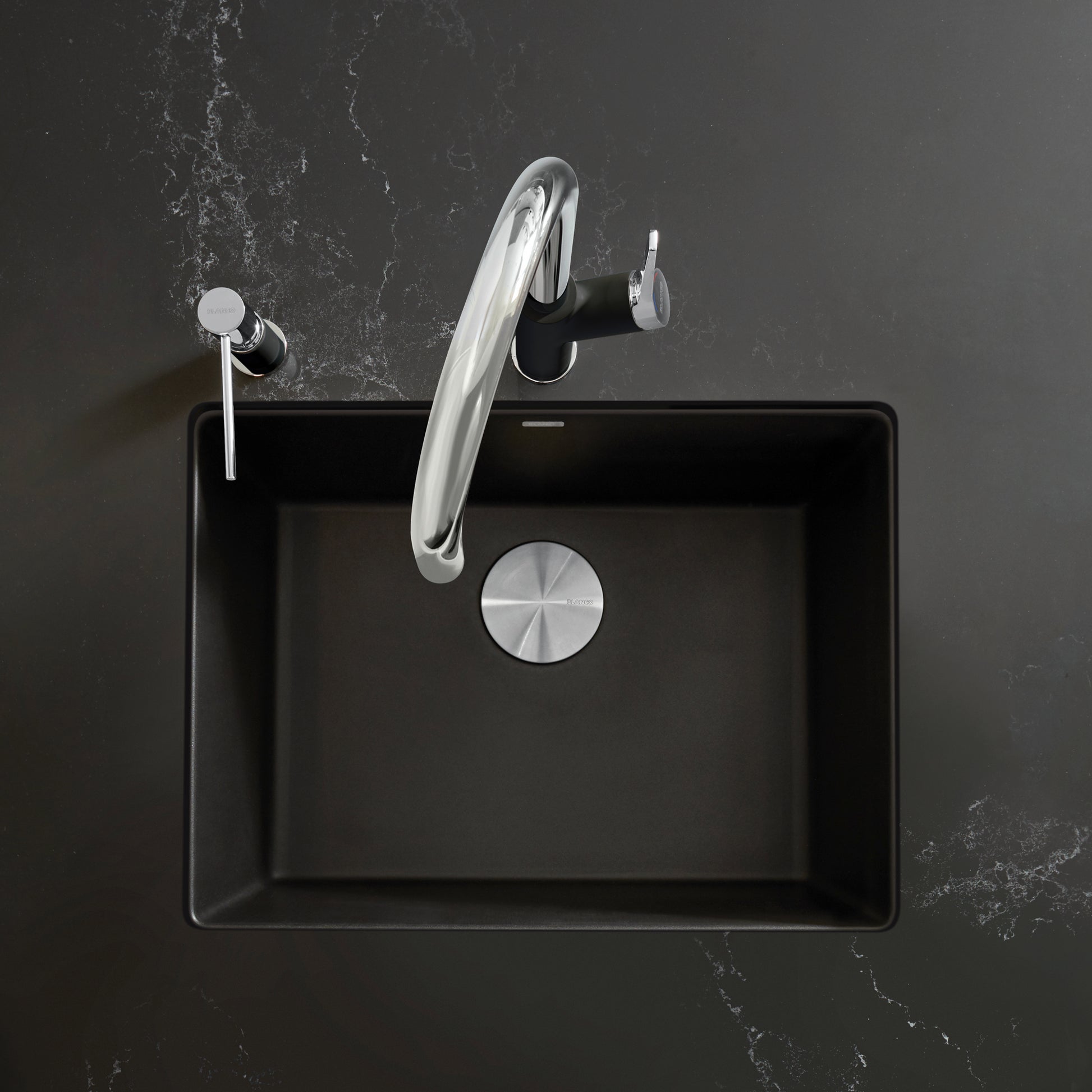 Coal black single-bowl kitchen sink with chrome curved faucet and drain strainer, shown from above.