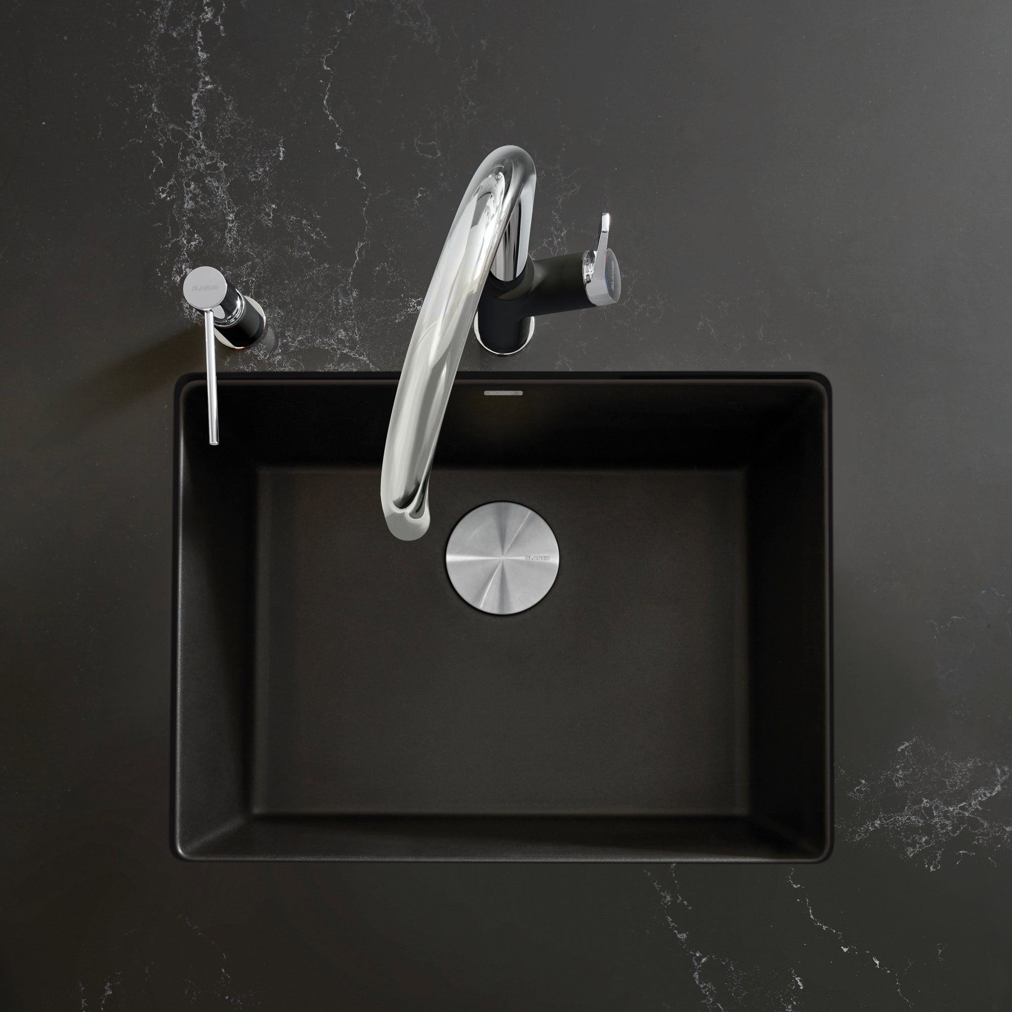 Coal black single-bowl kitchen sink with chrome curved faucet and drain strainer, shown from above.
