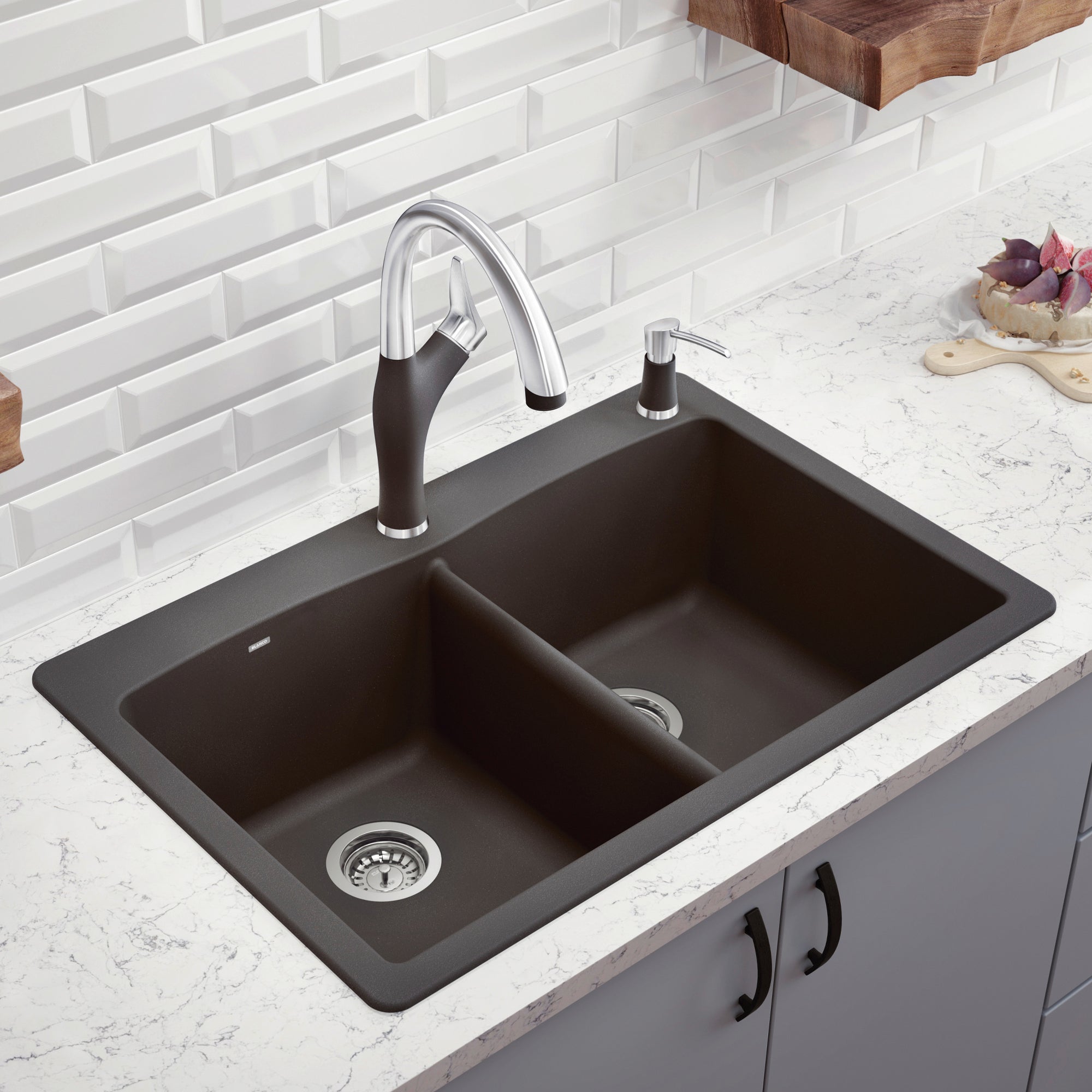 Dark gray double bowl drop-in kitchen sink with chrome faucet and soap dispenser installed in white countertop.