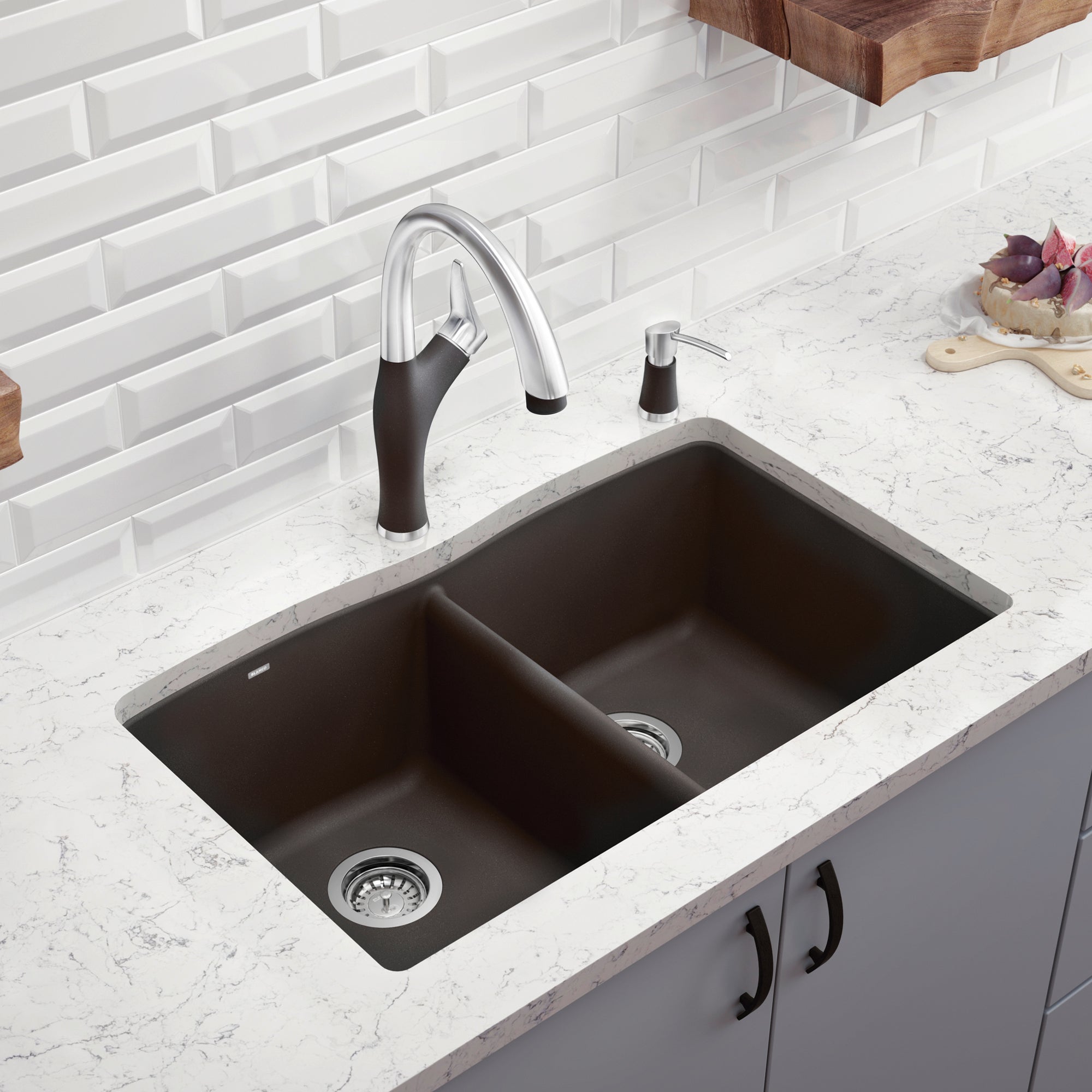 Dark gray double bowl drop-in kitchen sink with dual stainless steel faucet and soap dispenser on white countertop.