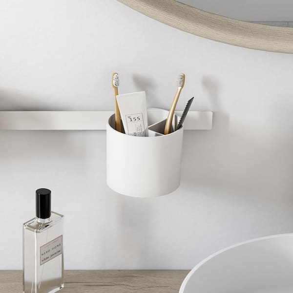 Matte white cylindrical wall-mounted tumbler holding toothbrushes and writing implements.
