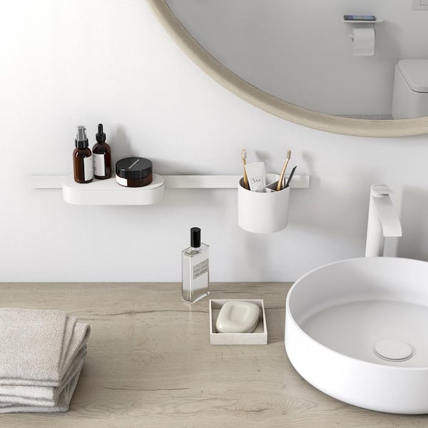 Matte white cylindrical tumbler displayed on bathroom counter next to sink and toiletries.