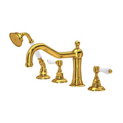 Unlacquered brass deck mount tub filler with curved spout, showerhead, and four control handles with white porcelain accents.