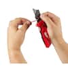 Red folding utility knife with blade storage compartment, held open in hands showing internal mechanism.