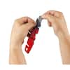 Red folding utility knife with blade storage compartment, held open in hands against white background.