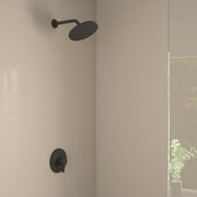 Matte black shower set with round overhead showerhead and wall-mounted pressure balance valve in tiled bathroom.