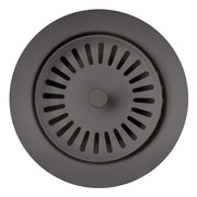 Cinder-colored metal basket strainer with radial slot perforations and central drain hole, viewed from above.