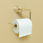Polished nickel toilet paper holder with curved arm and cylindrical finial, mounted on wall with white roll inserted.