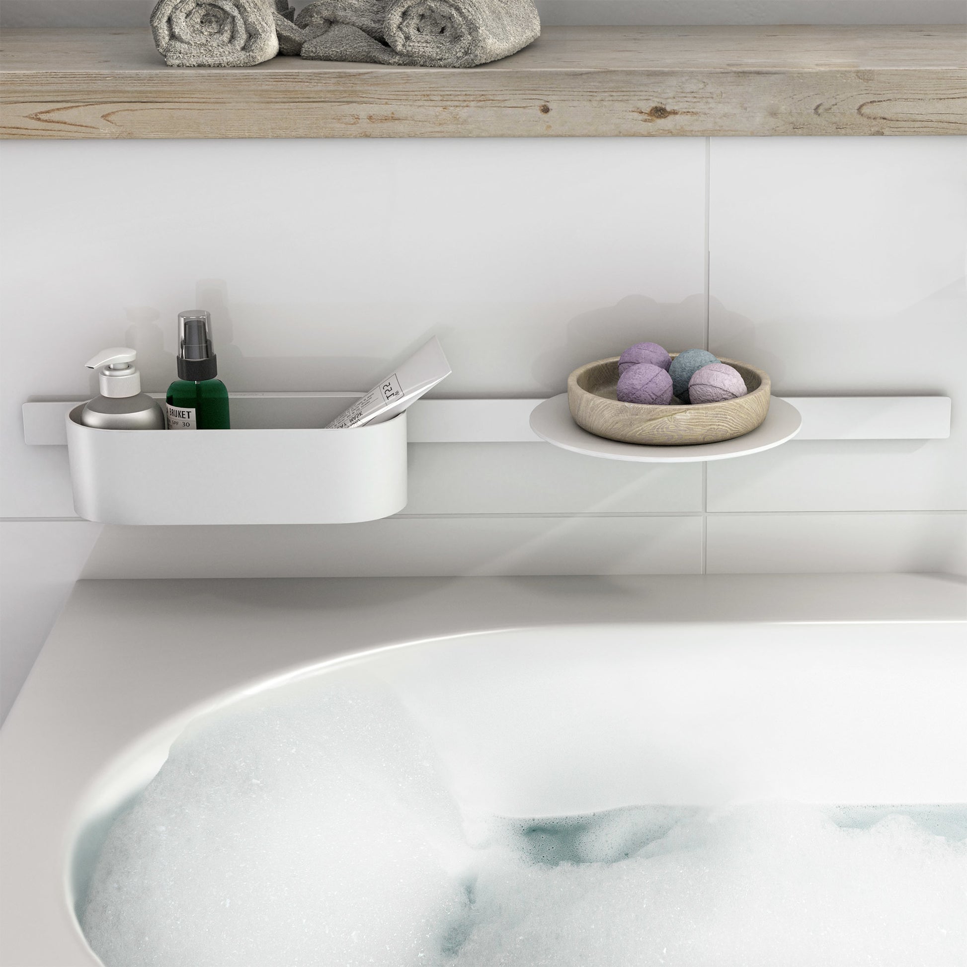 Matte white wall-mounted storage basket with rounded edges holding bathroom items above a bathtub.