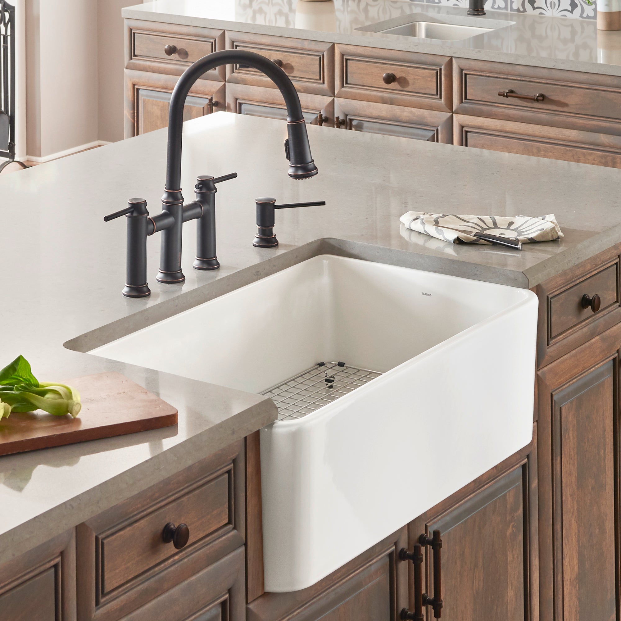 White ceramic single bowl apron sink installed in wood cabinetry with black faucet and gray countertop.