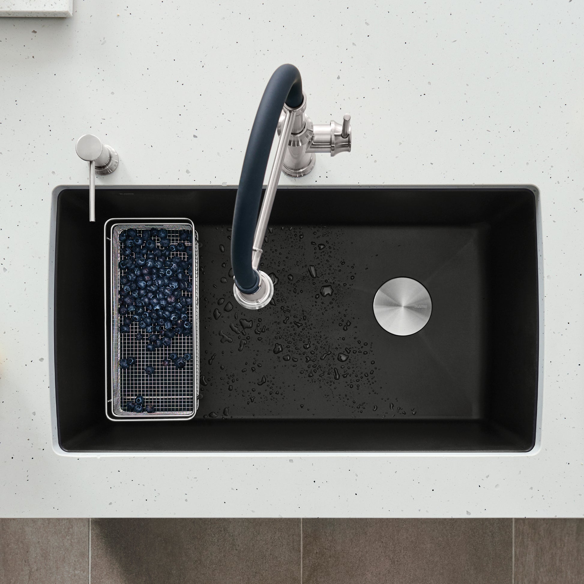 Coal black single bowl kitchen sink with faucet and drain strainer, viewed from above.