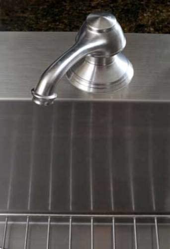 Polished chrome wall-mounted bathtub spout with curved outlet positioned above dark tile surface.