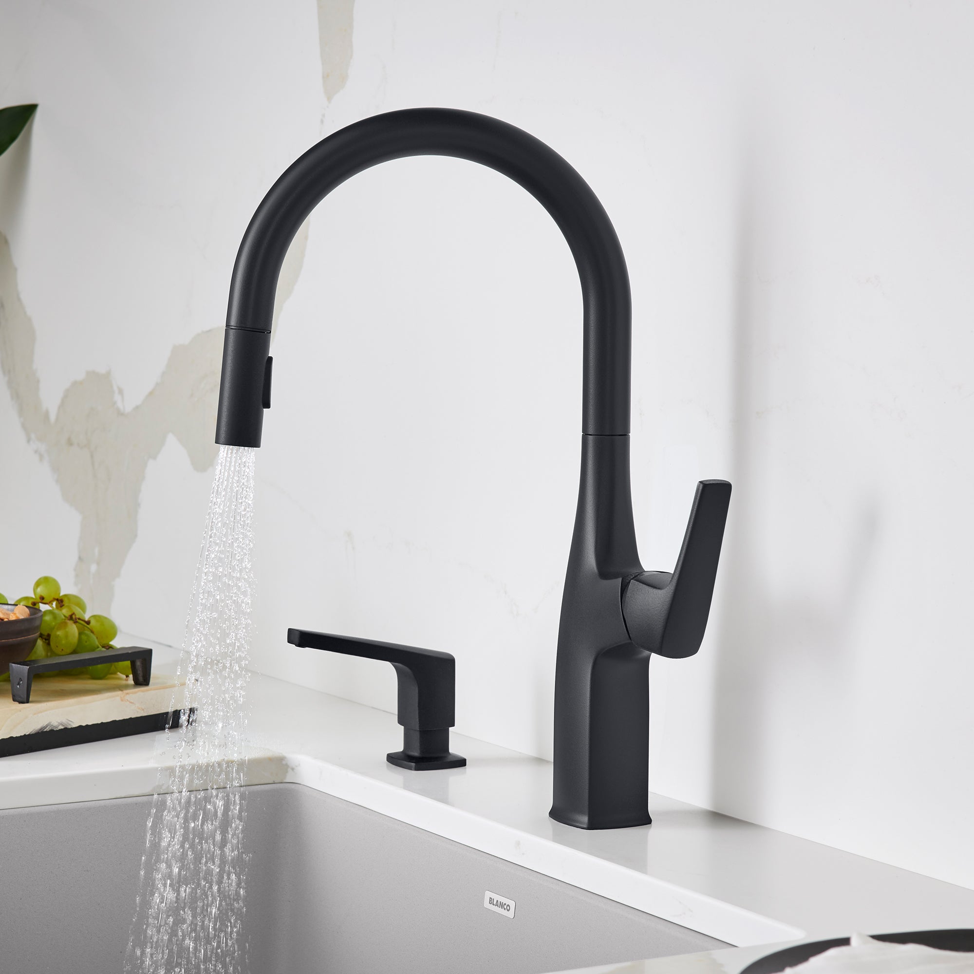 Matte black pull-down kitchen faucet with curved spout and single lever handle, shown with water flowing into sink.