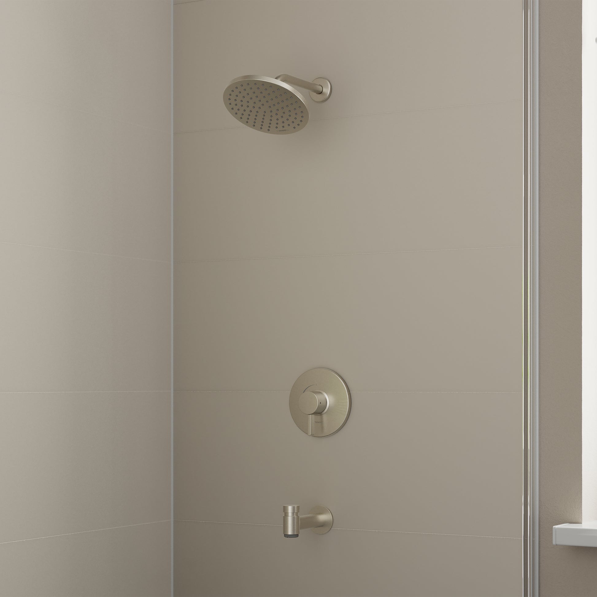 Brushed nickel shower set with round showerhead, circular valve trim, and tub spout mounted on tile wall.