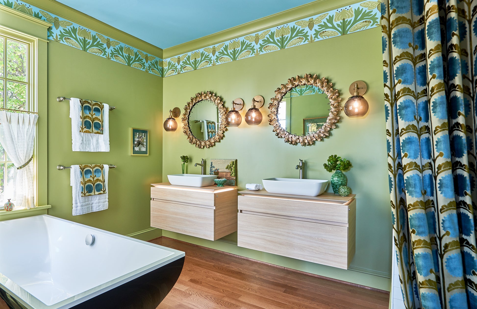 Brushed nickel towel bar mounted on green bathroom wall above wooden vanity with white vessel sinks.