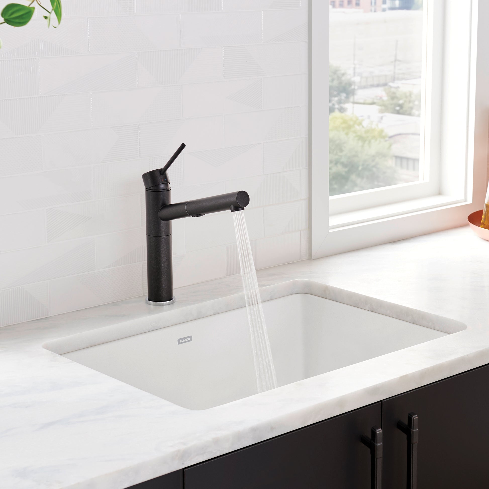 White rectangular kitchen sink with black pull-down faucet installed in marble countertop.