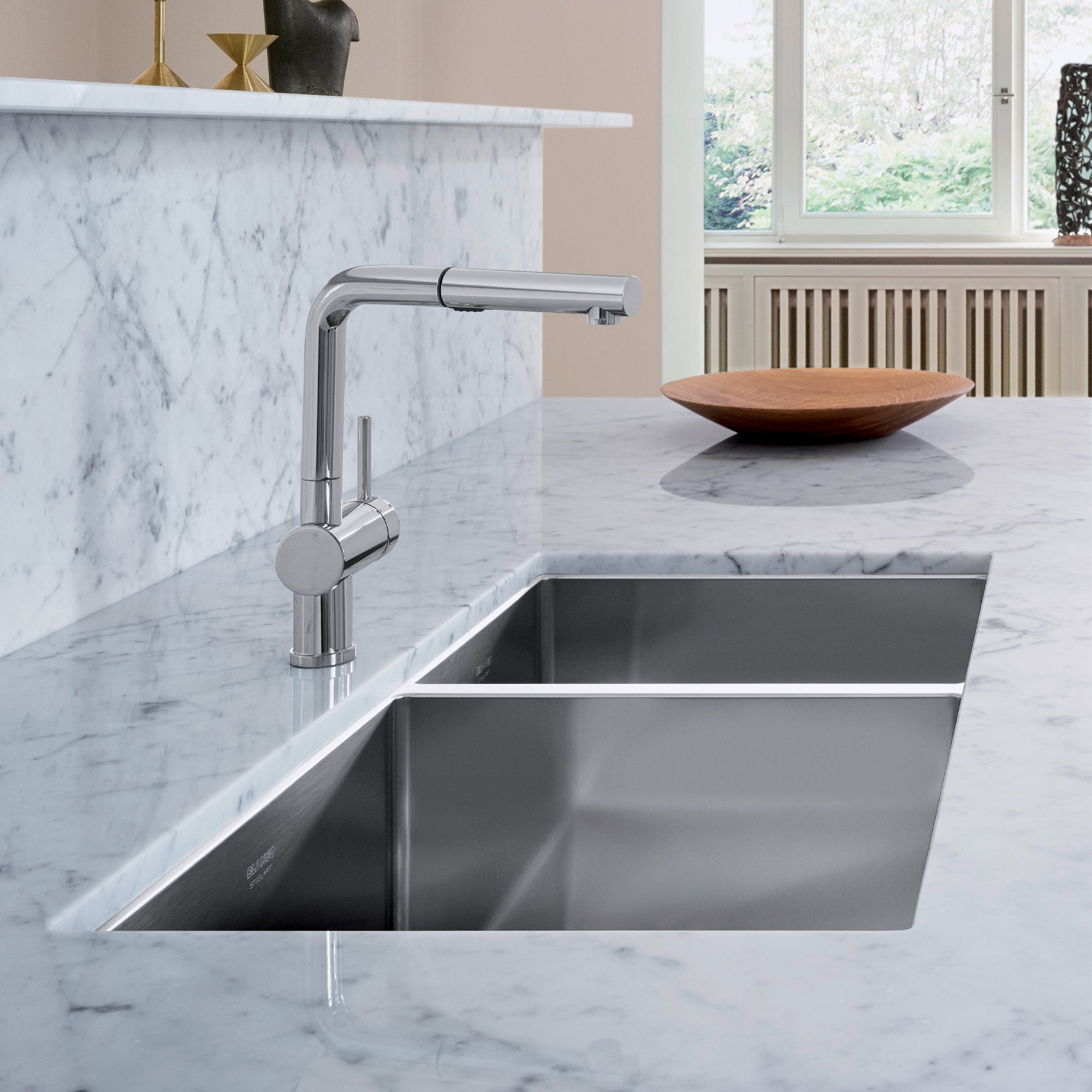 Stainless steel undermount kitchen sink with two bowls and chrome faucet installed in marble countertop.