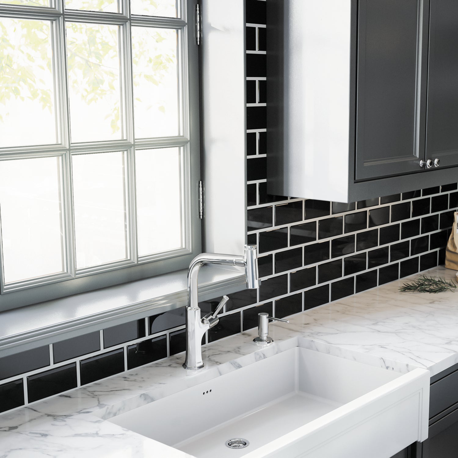 Chrome soap dispenser with cylindrical pump mounted on marble countertop next to white farmhouse sink.