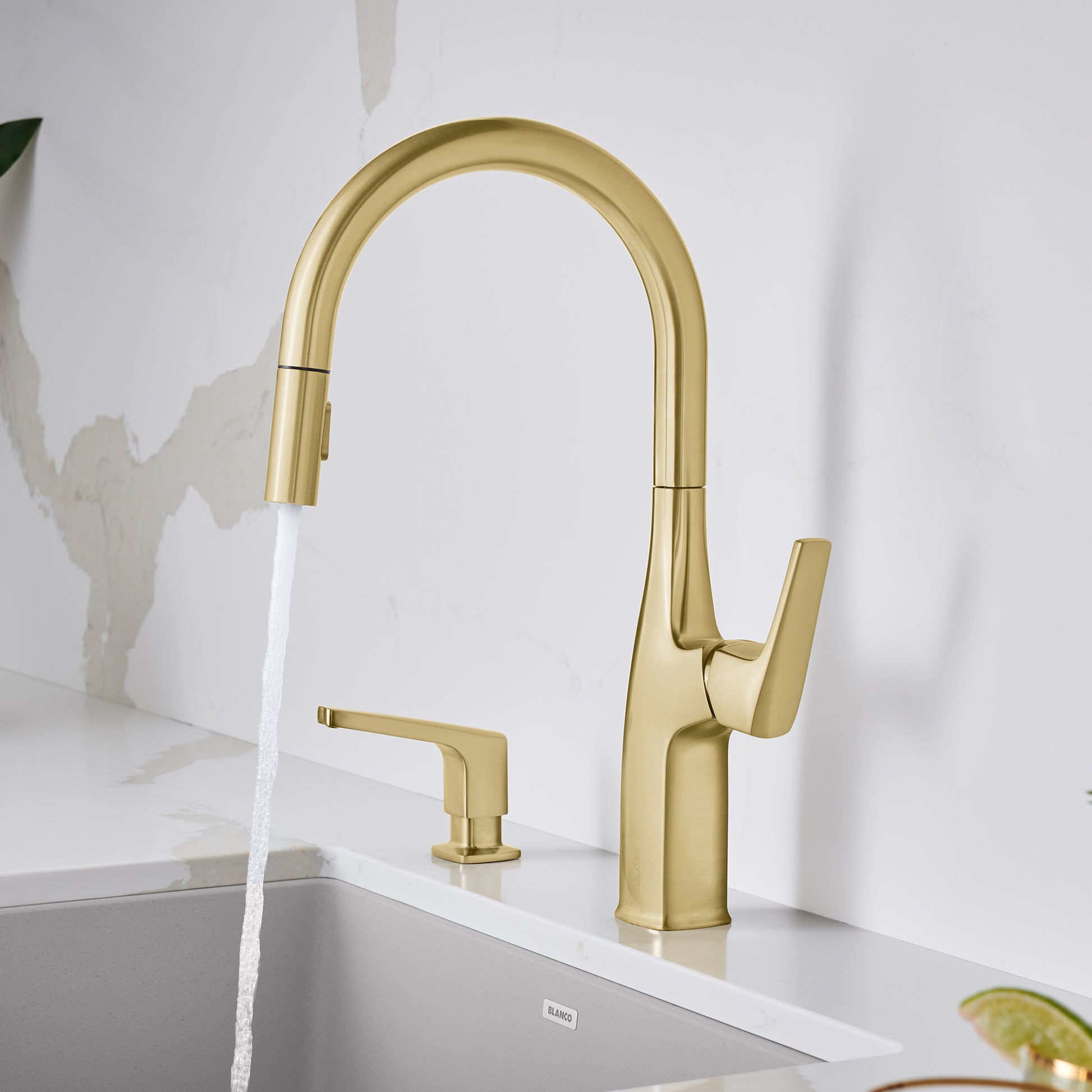 Satin gold pull-down kitchen faucet with high arched spout, single lever handle, and matching soap dispenser on white sink.