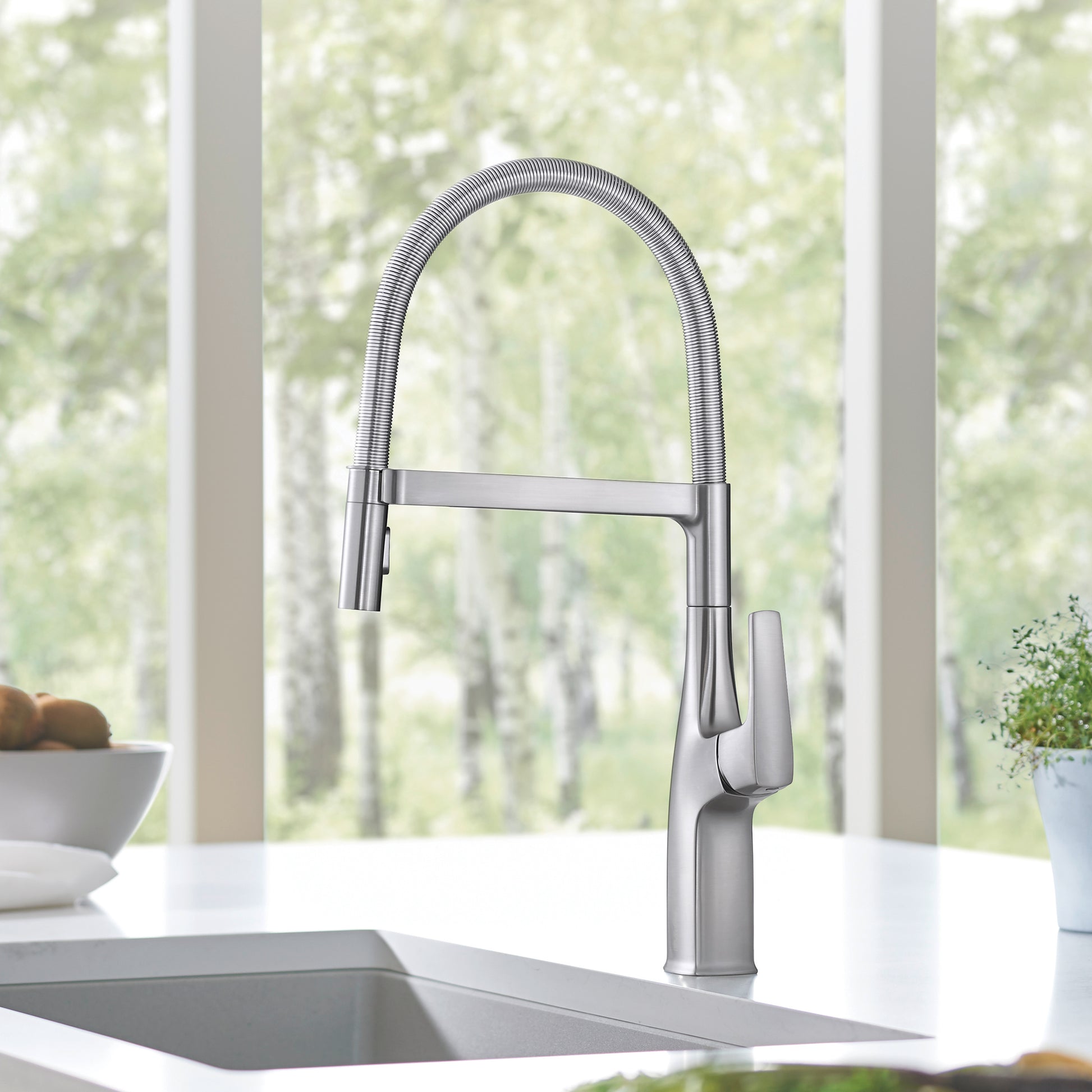 Stainless steel semi-pro kitchen faucet with tall arched spout, flexible hose, and single lever handle mounted above sink.