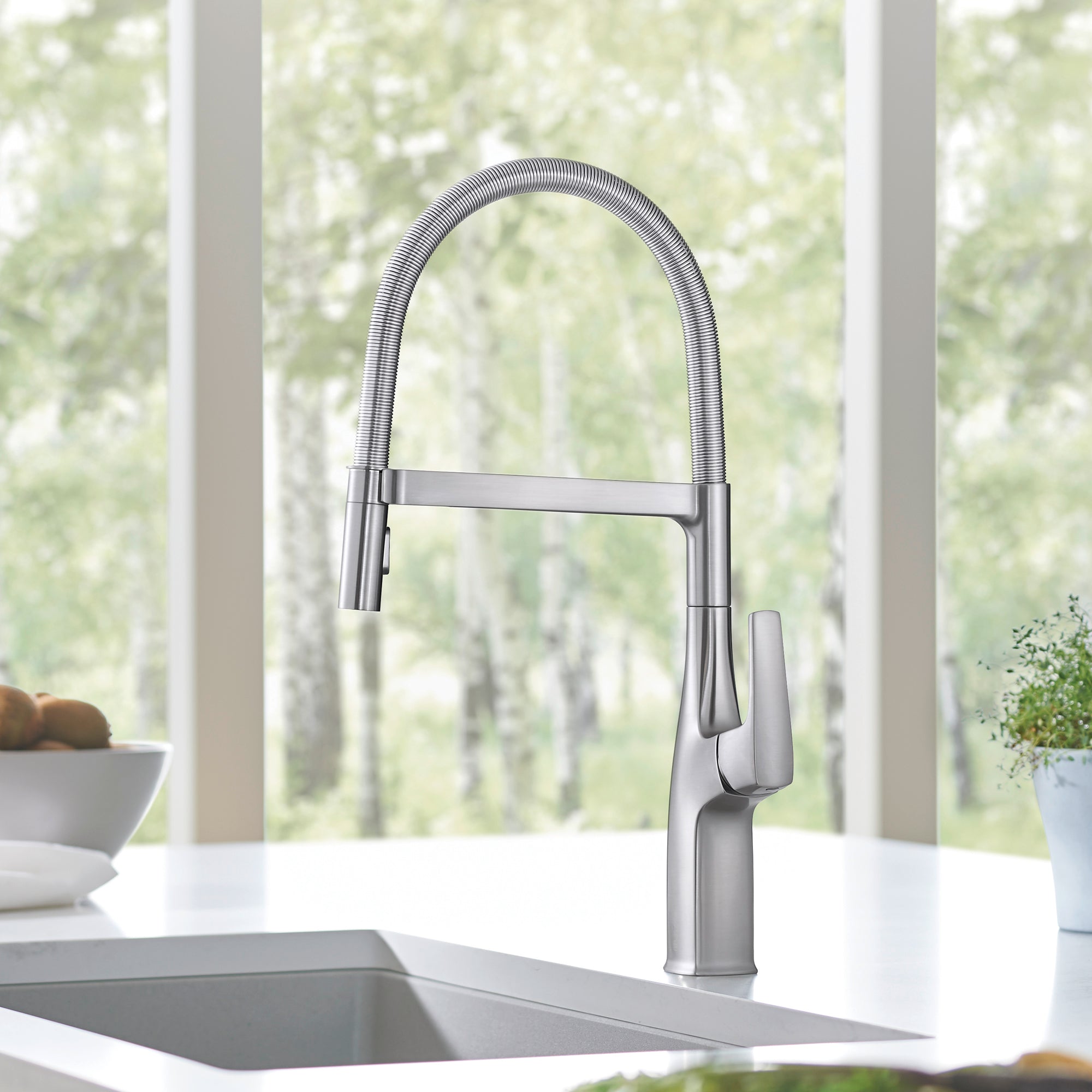 Stainless steel semi-pro kitchen faucet with tall arched spout, flexible hose, and single lever handle mounted above sink.