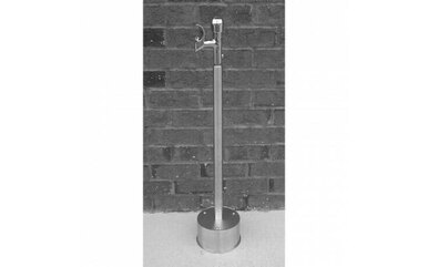 Stainless steel freestanding drinking fountain with single spout and circular base on concrete surface.