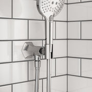 Chrome handshower holder with outlet mounted on white subway tile wall, featuring perforated showerhead above.